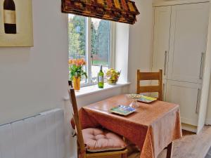 a dining room table with two chairs and a window at Wheatsheaf Cottage in Nun Monkton
