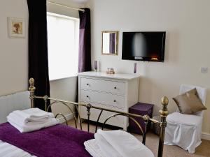 1 dormitorio con 1 cama, TV y vestidor en Wheatsheaf Cottage en Nun Monkton