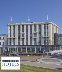 a large white building with a sign in front of it at Michels Strandhotel Germania in Norderney