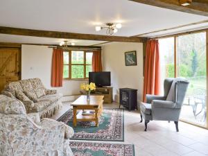 a living room with a couch and chairs and a tv at Butlers Barn in Darsham