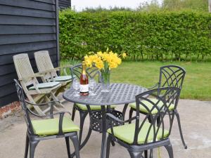 a table with chairs and a bottle of beer and flowers at Butlers Barn in Darsham