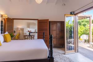 a bedroom with a bed and a patio at Habitation Saint Charles - Hôtel de Charme & Spa in Petit-Bourg
