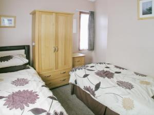 Schlafzimmer mit einem Bett und einem Holzschrank in der Unterkunft Summer Time in Brundall