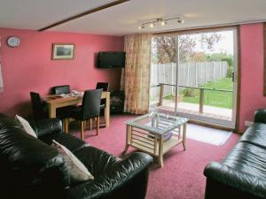 a living room with a leather couch and a table and a dining room at Summer Time in Brundall