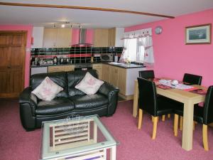 ein Wohnzimmer mit einem schwarzen Ledersofa und einem Tisch in der Unterkunft Summer Time in Brundall