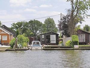 una casa en un muelle con un barco en el agua en Summer Time en Brundall