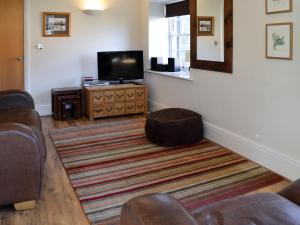 a living room with a couch and a television at Sail Loft Apartment in Whitby