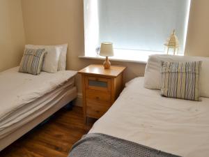 um quarto com 2 camas e uma mesa de cabeceira com uma janela em Sail Loft Apartment em Whitby