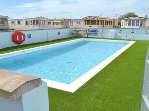 a large swimming pool with green grass and houses at White Towers - Hw7625 in Llanwnda