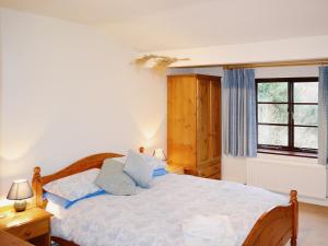 a bedroom with a bed with blue pillows and a window at Heol Llygoden in Cathedine