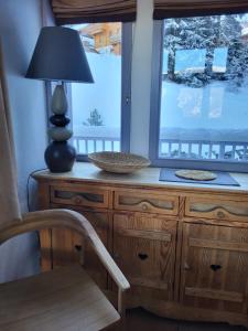 una lámpara sentada en un tocador de madera junto a una ventana en Chalet Courchevel La Tania - 14 personnes - 7 chambres 7 salles de bains - 40 m des pistes, en Courchevel