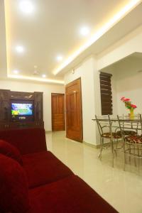 Una sala de estar con un sofá, una mesa y un televisor. en Citadel Inn Serviced Apartments, en Kochi