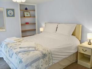 a bedroom with a white bed and a night stand at Beech Cottage in Kirkby on Bain