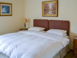 a bedroom with a large bed with white sheets at Grooms Cottage in Elsdon
