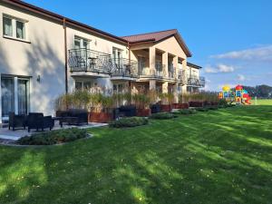 een gebouw met een tuin met stoelen en een speeltuin bij POKOJE GOŚCINNE LAWENDOWY DWÓR in Mikoszewo