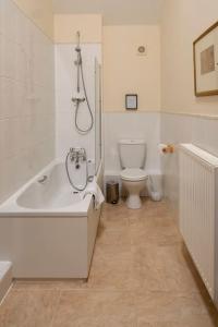 a white bathroom with a tub and a toilet at Wheelhouse Cottage . A brick-built barn conversion in Thirsk