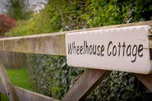 un cartel en una valla de madera que lee Wherehouse cafe en Wheelhouse Cottage . A brick-built barn conversion, en Thirsk