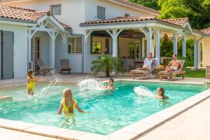 a group of people playing in a swimming pool at Habitation Saint Charles - Hôtel de Charme & Spa in Petit-Bourg