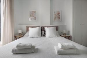 a bedroom with a white bed with two towels on it at Tejares Sevilla Luxury Penthouse en Triana - gran terraza, piscina & parking privados in Seville