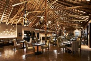 a dining room with tables and chairs and wooden ceilings at Letamo at Qwabi Private Game Reserve by NEWMARK in Bela-Bela