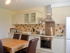 a kitchen with white cabinets and a wooden table at Paddock Cottage in Orford