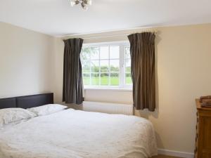 a bedroom with a bed and a window at Paddock Cottage in Orford