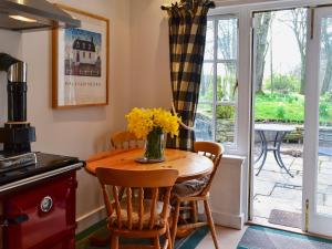 a kitchen with a table with yellow flowers on it at Gardener's Cottage in Skirling