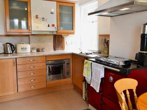 a kitchen with wooden cabinets and a red stove top oven at Gardener's Cottage in Skirling