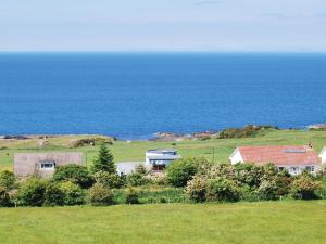 a house in a field with the ocean in the background at Island View in Dunure