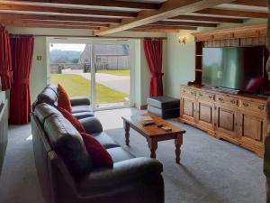 ein Wohnzimmer mit Sofas und einem Flachbild-TV in der Unterkunft Meadowside Cottage in Calton