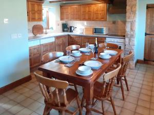een keuken met een houten tafel en stoelen bij Meadowside Cottage in Calton