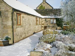 ein Steinhaus mit Schnee auf dem Boden in der Unterkunft Meadowside Cottage in Calton