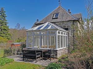 a glass house with a table and chairs in it at The Coach House in Birnam