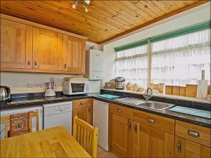 a kitchen with wooden cabinets and a table with a microwave at The Coach House in Birnam