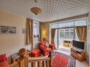 a living room with a tv and a couch and a chair at The Coach House in Birnam