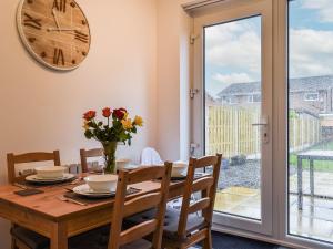 a dining room with a table and chairs and a clock at Excalibur Cottage in Saint Annes on the Sea