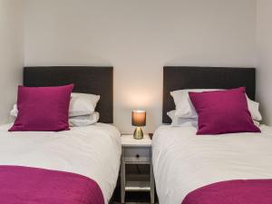 two beds with purple pillows in a bedroom at Excalibur Cottage in Saint Annes on the Sea