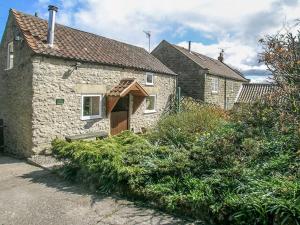 a stone house with an open door in a yard at Old Barn Cottage in Lockton