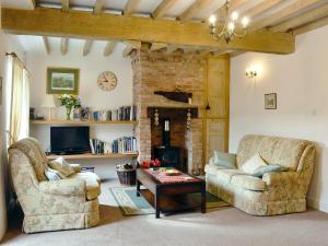 een woonkamer met 2 stoelen en een open haard bij Ostlers Cottage in Long Bennington