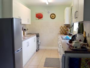 a kitchen with white cabinets and a black refrigerator at Ostlers Cottage in Long Bennington