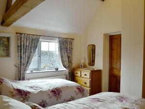 a bedroom with two beds and a window at Ostlers Cottage in Long Bennington