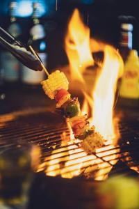 a piece of food on a spatula next to a fire at O' Hotel in Hong Kong