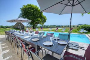 a long table with chairs and an umbrella next to a pool at Crazy Villa Gilliere 61 - Heated pool - Basket - 2h Paris - 30p in Montchevrel