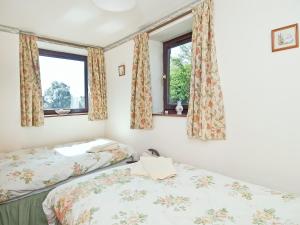 two beds in a room with two windows at Jerusalem Cottage in Longnor