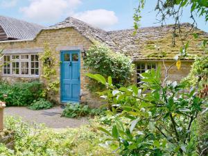 an old stone house with a blue door at The Hunting Lodge in Wyck Rissington