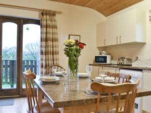 cocina y comedor con mesa y sillas en Woodside Lodge - Hw7520 en Penybont