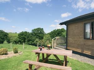 einen hölzernen Picknicktisch im Gras neben einem Gebäude in der Unterkunft Woodside Lodge - Hw7520 in Penybont