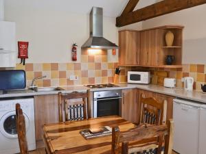 uma cozinha com uma mesa e um fogão forno superior em Oregano - E4483 em Ludham