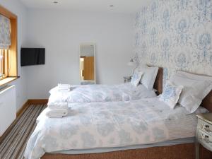 a bedroom with two beds and a tv on a wall at Carr End Barn B in Preesall