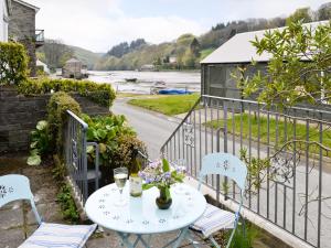 a table and chairs on a balcony with a view of a river at Watercolour Cottage in Lerryn